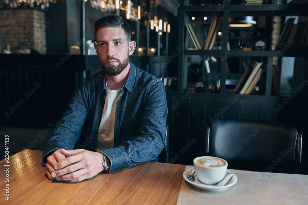 Confident man enjoying a cup of coffee while having work break lunch in indoors cafe looking pensive Confident man enjoying a cup of coffee while having work break lunch in indoors cafe looking pensive