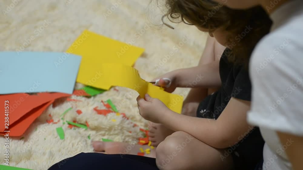 Mother helping her child to cut colored paper. Mother helping her child to cut colored paper.