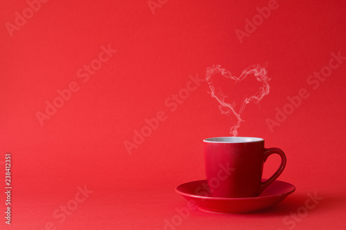 Cup of tea or coffee with steam in one heart shape on red background. Valentine s day celebration or love concept. Copy space