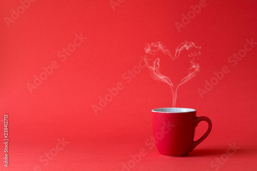 Cup of tea or coffee with steam in one heart shape on red background. Valentine's day celebration or love concept. Copy space