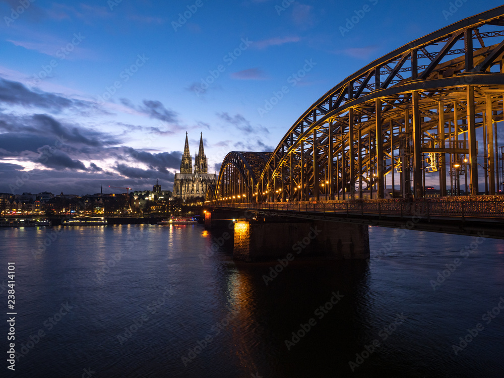Fototapeta premium December 2018: Sunset sky with clouds over the city skyline Cologne with Bridge and Köln Dom ,Evening scene over Cologne/Koln city with Kolner Dom/Cathedral behind the Hohenzollern bridge