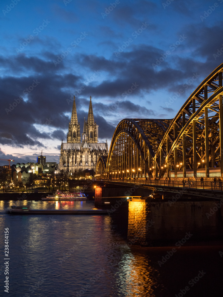 Fototapeta premium December 2018: Sunset sky with clouds over the city skyline Cologne with Bridge and Köln Dom ,Evening scene over Cologne/Koln city with Kolner Dom/Cathedral behind the Hohenzollern bridge