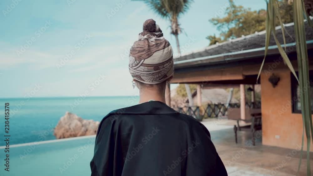 following shot of glamour young woman walking to the swimming pool at luxury villa near the ocean following shot of glamour young woman walking to the swimming pool at luxury villa near the ocean
