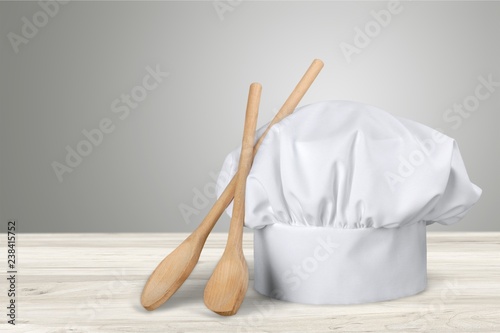 White cooks cap and wooden spoons on wooden table