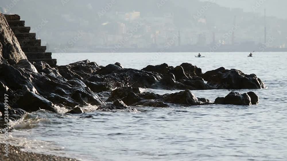 Waves beat on the rocks. Two koyaks are floating in the rear. Waves beat on the rocks. Two koyaks are floating in the rear.