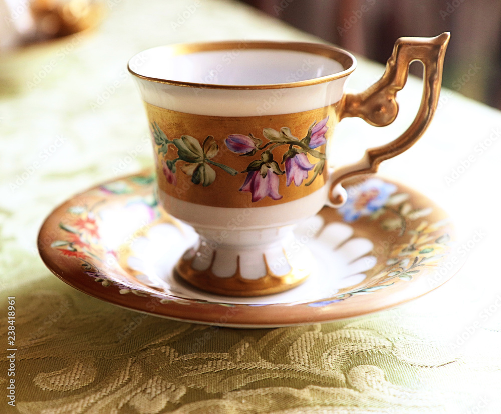 Fototapeta premium Romantic antique coffee cup with saucer in Biedermaier style, hand painted in gold and enamel with colorful flowers