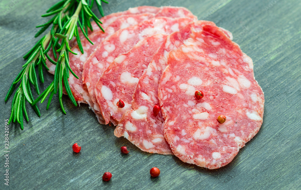slices of salami with red and black pepper on wood slices of salami with red and black pepper on wood