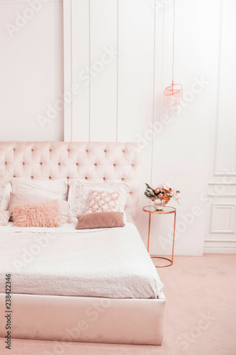 White-pink bedroom with large bed and many pillows on it