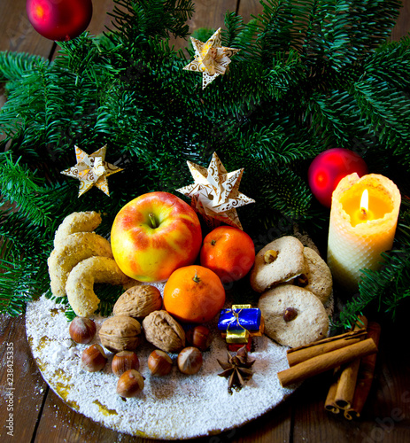 traditional german christmas sweets plate with fruits, nuts aqnd cookies, decorated with spices, fir branches and paper stars photo