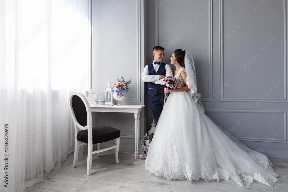 bride and groom and a stylish white room
newlyweds in a stylish interior
the groom gently looks at the bride