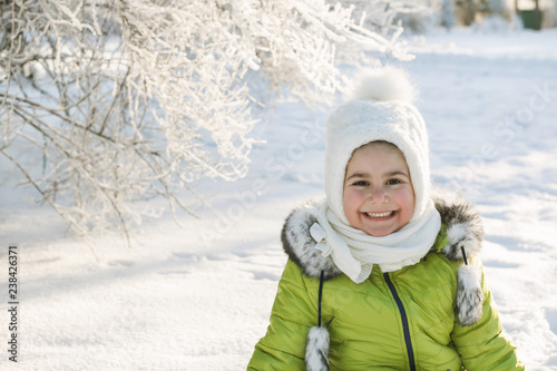 Happy little girl in bright winter clothes having fun in the snow