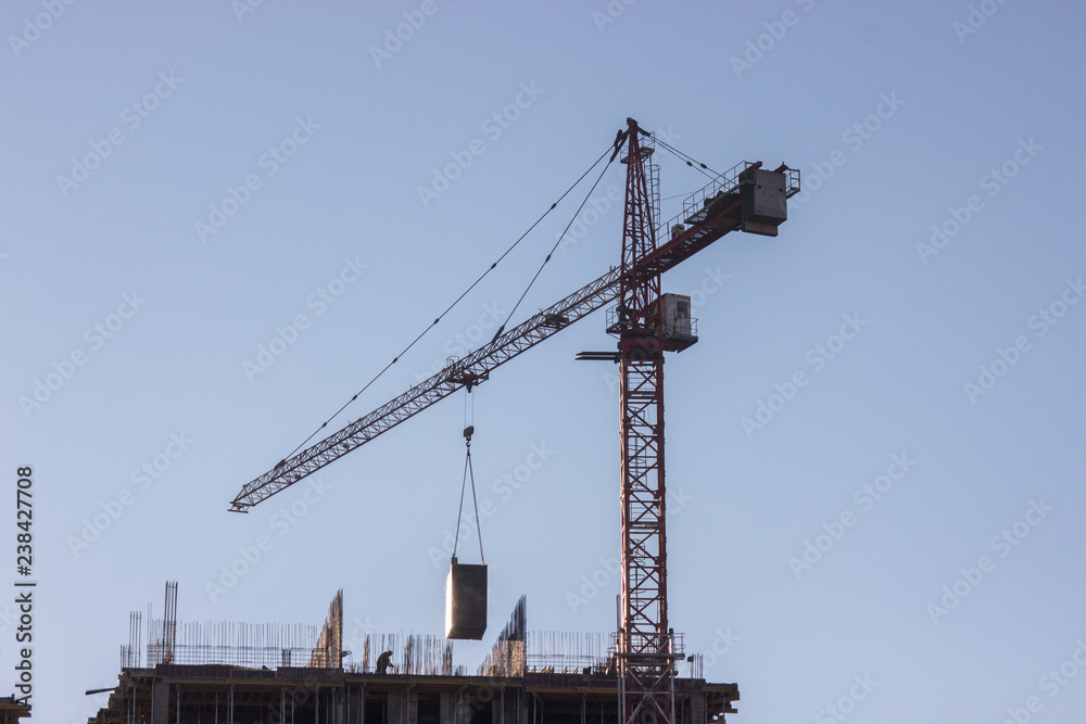 Construction site with yellow crane on blue sky background. Construction, construction work, lifting heavy loads up