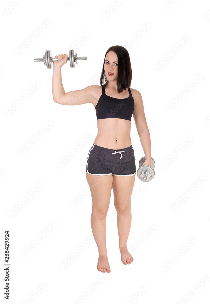 Woman standing bare feet and lifting two dumbbells Woman standing bare feet and lifting two dumbbells