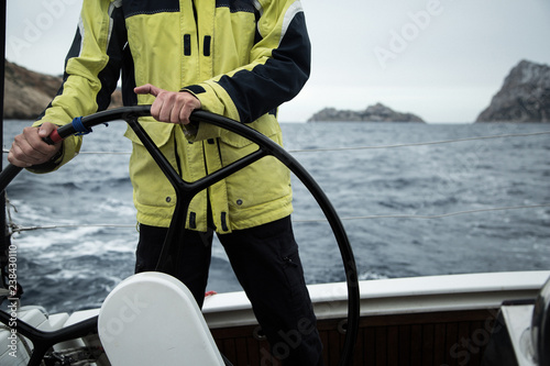 A sailing yacht skipper is at the helm. Close-up. It's cold, waves.