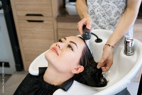 Hairdresser salon. Beautiful brunette woman during hair wash