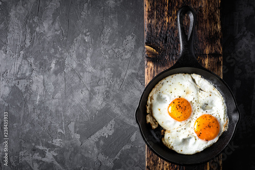 fried eggs in black skillet top view with space for a text photo