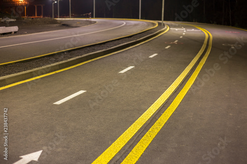 Wide modern smooth empty asphalt highway sharp turn sharp with bright white and double yellow marking sign line. Speed, safety, comfortable journey and professional road building concept.
