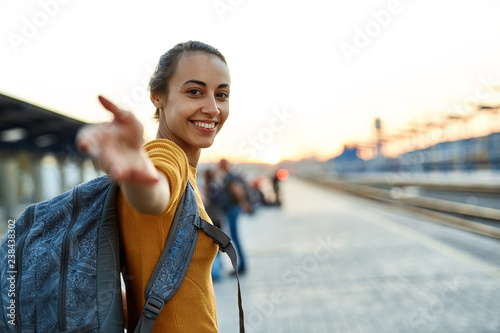 portrait of a young woman traveler with small backpack on the railway stantion