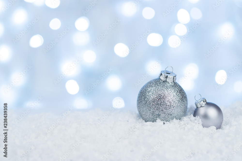 Silver Christmas balls on snow with defocused white light Silver Christmas balls on snow with defocused white light