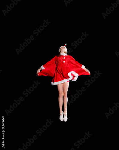 Christmas time, childhood, fairy tale. A young girl wearing a Santa's costume is flying photo