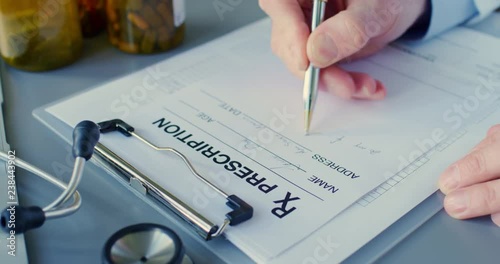 Male Doctor Writing Rx Prescription On Clipboard At Desk 4K