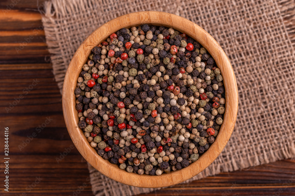 Mix of peppers in bowl burlap napkin on wooden background Mix of peppers in bowl burlap napkin on wooden background