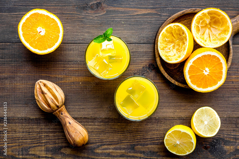 Squeeze fresh oranges with juicer. Orange juice in glass near half cut oranges on dark wooden background top view Squeeze fresh oranges with juicer. Orange juice in glass near half cut oranges on dark wooden background top view