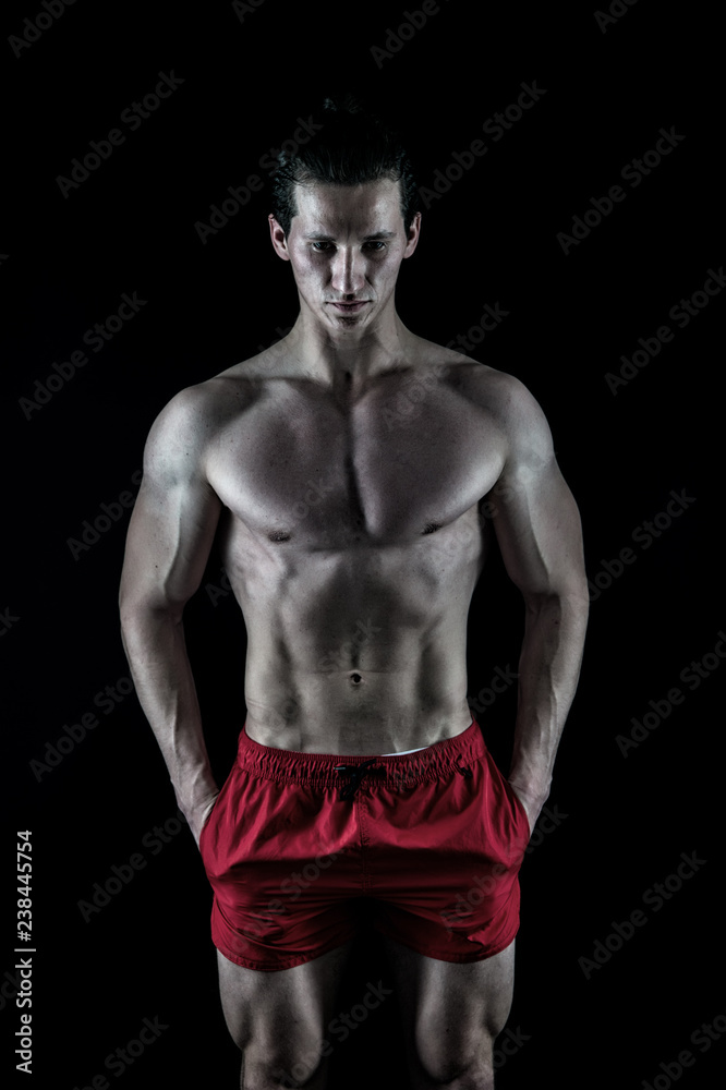 Man muscular macho posing with bare torso on black background. Guy muscular athlete put hands in pockets. Attractive macho calm face. Muscular bodybuilder keep calm. Perfect male body concept