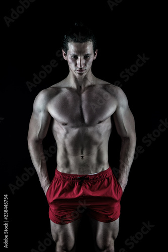 Man muscular macho posing with bare torso on black background. Guy muscular athlete put hands in pockets. Attractive macho calm face. Muscular bodybuilder keep calm. Perfect male body concept © be free