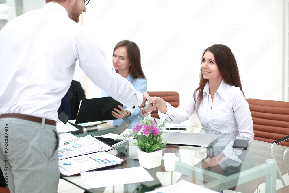 man and woman partners shaking hands over the table, maintaining eye contact man and woman partners shaking hands over the table, maintaining eye contact