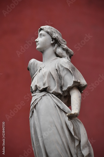 A sandstone sculpture of an angel whose right arm has broken off. 