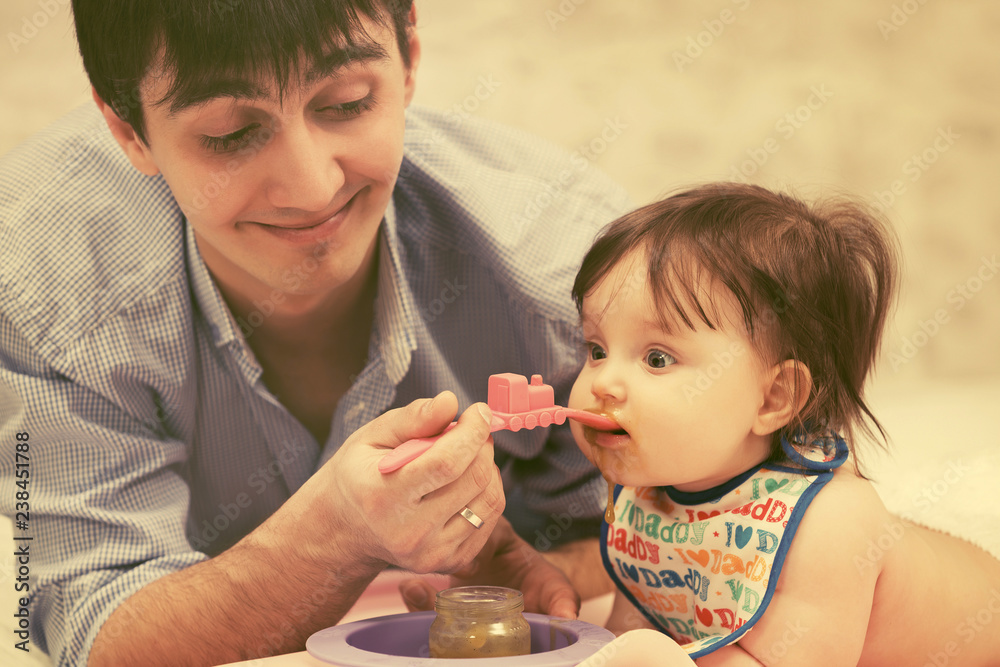 Happy father feeding baby girl at home Happy father feeding baby girl at home