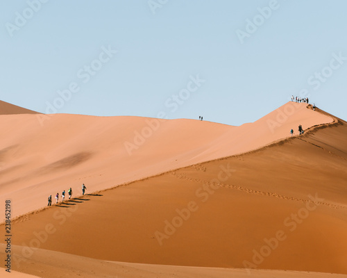 People walking along a sand dune
