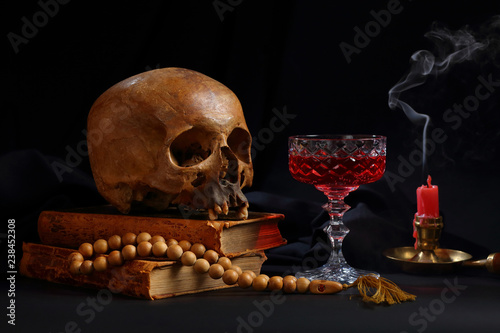 A skull, a rosary, a glass of wine and an unlit candle photo