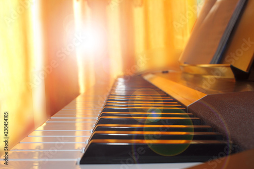 Piano keys before piano lessons at home, close up in the sun's rays, toned