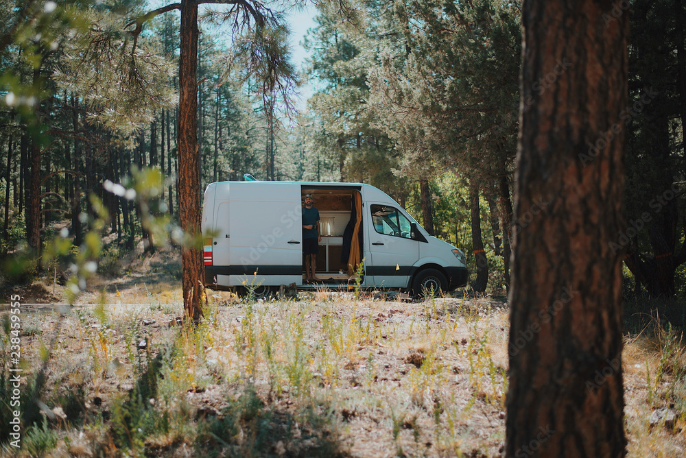 Man standing amidst trees in motor home at forest Man standing amidst trees in motor home at forest
