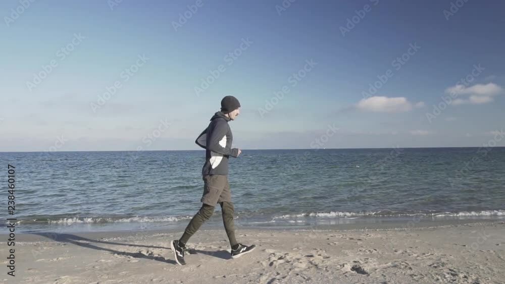 Young male runner training outdoors in the cold weather, athlete workout on the autumn beach Young male runner training outdoors in the cold weather, athlete workout on the autumn beach