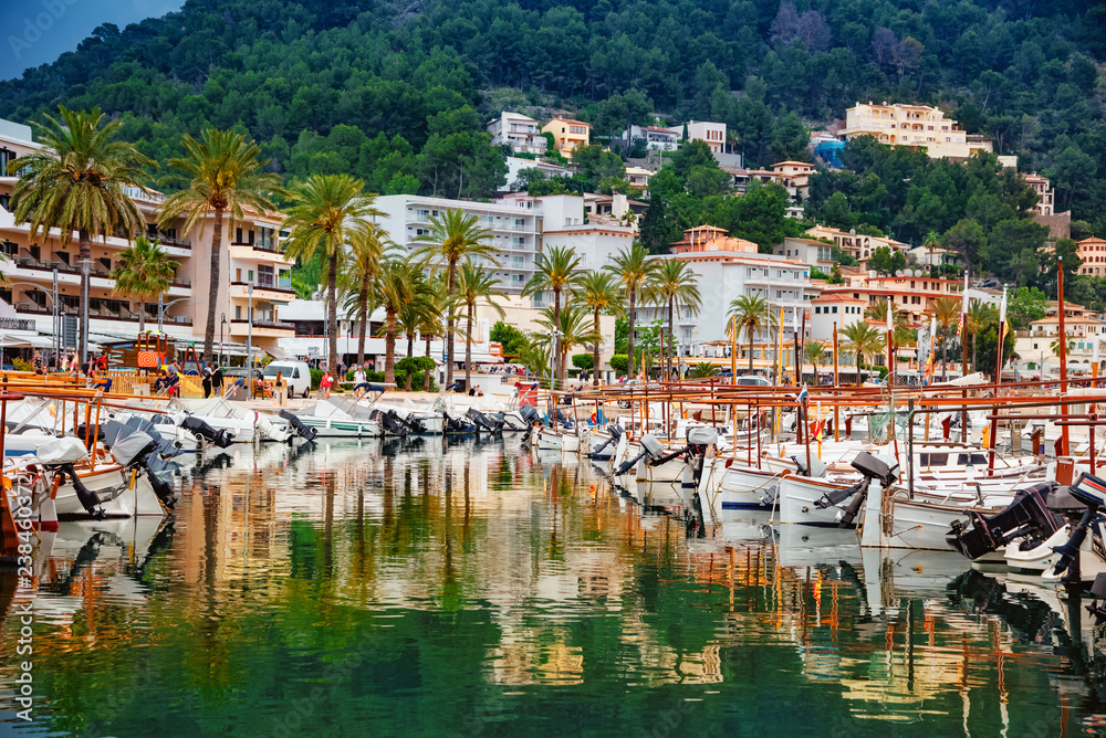 Wide view of Port de Soller harbor and boats reflected in the water on Mallorca island