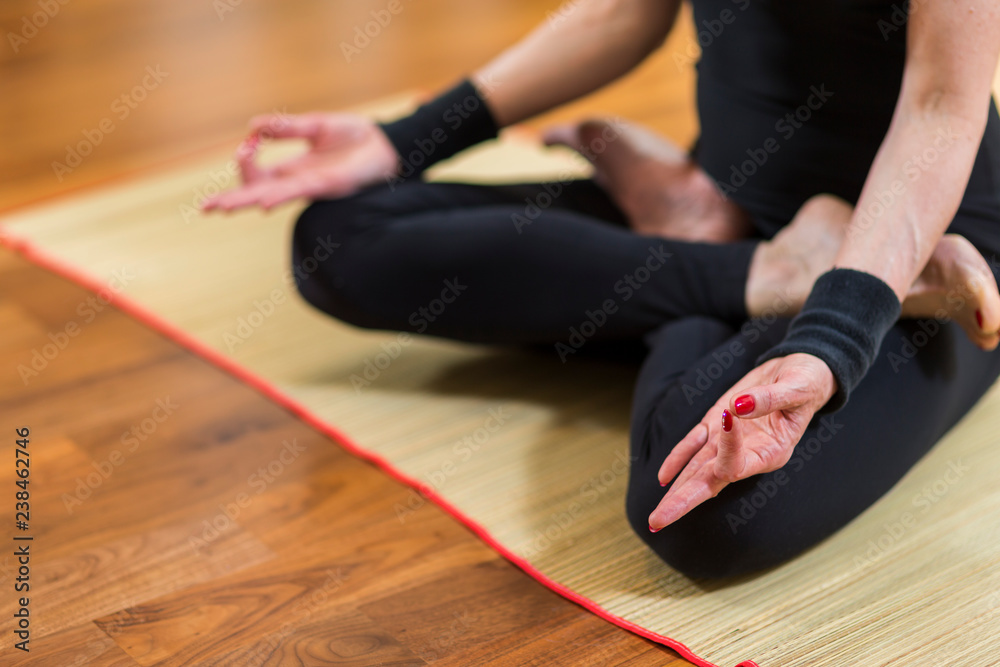 Closeup of Both Hands of Caucasian Brunette Woman Practicing Yoga Indoors. Doing Sukhasana Exercises In Lotus Therapy Pose. In Front of Sunny Window in Background.
