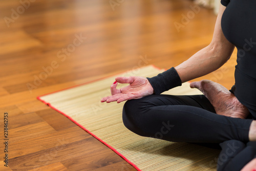Closeup of Hand of Caucasian Brunette Woman Practicing Yoga Indoors. Doing Sukhasana Exercises In Lotus Therapy Pose. In Front of Sunny Window in Background.