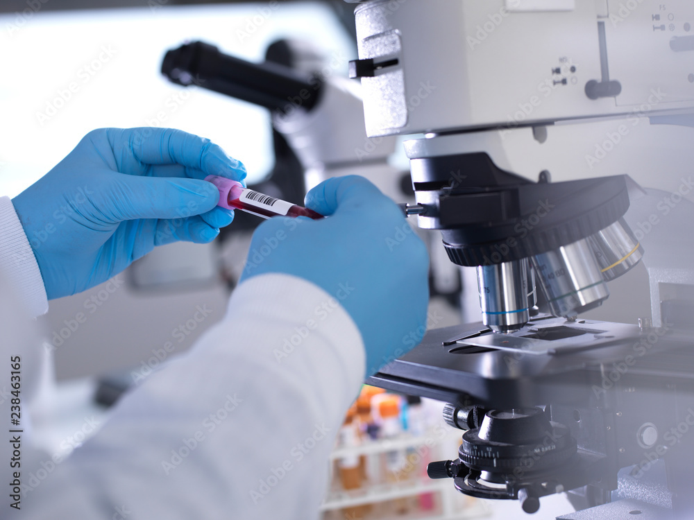 Cropped hands of male scientist holding blood samples by microscope in laboratory Cropped hands of male scientist holding blood samples by microscope in laboratory