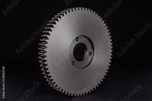 Plastic, black gear with 68 sprockets, isolated on a black background.