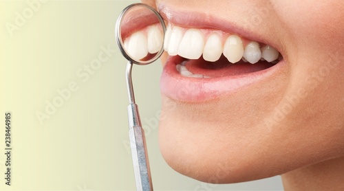 Woman teeth and a dentist mouth mirror on background