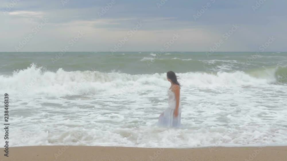 girl walks on the beach, the water wets her dress girl walks on the beach, the water wets her dress