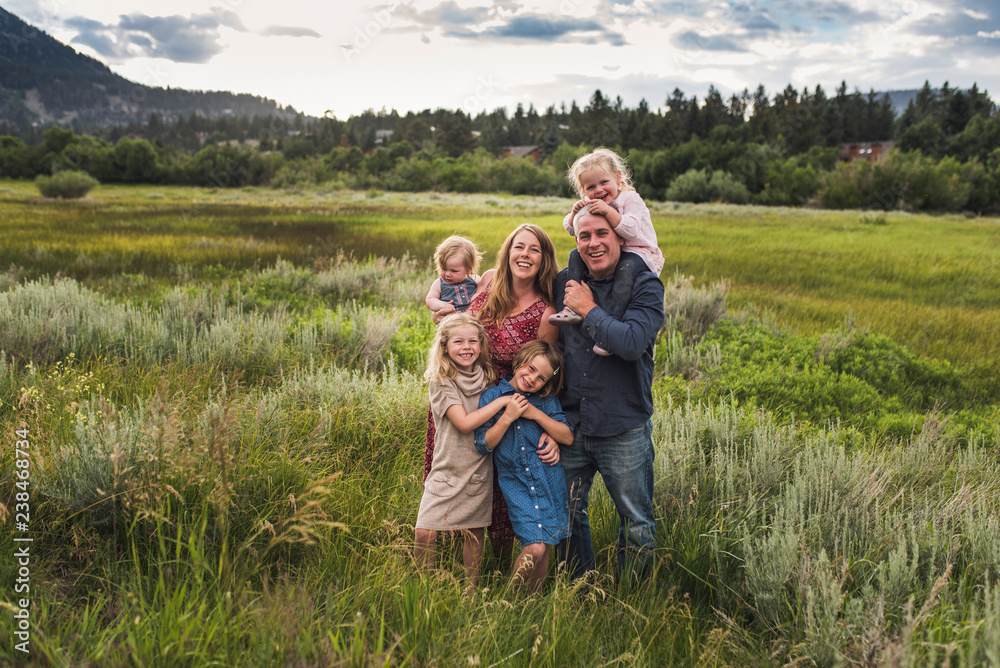 Portrait of smiling family standing in grassy field against cloudy sky Portrait of smiling family standing in grassy field against cloudy sky