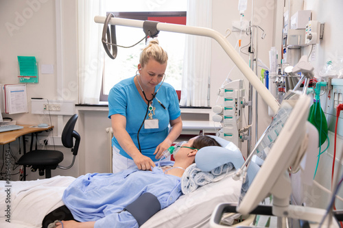 Female doctor examining patient lying on bed in hospital photo