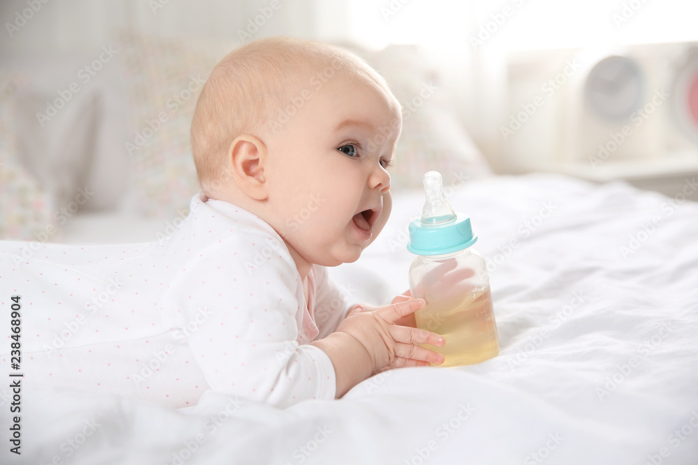 Pretty baby lying with bottle on bed at home Pretty baby lying with bottle on bed at home