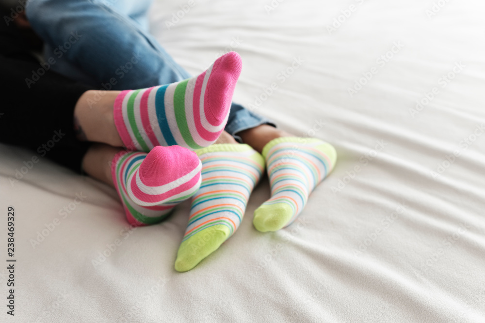 Low section of lesbian couple wearing colorful socks while relaxing on bed  at home Stock Photo | Adobe Stock