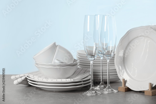 Set of clean dishes on table against light background