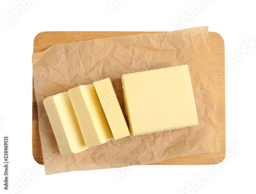 Wooden board with cut block of butter on white background, top view